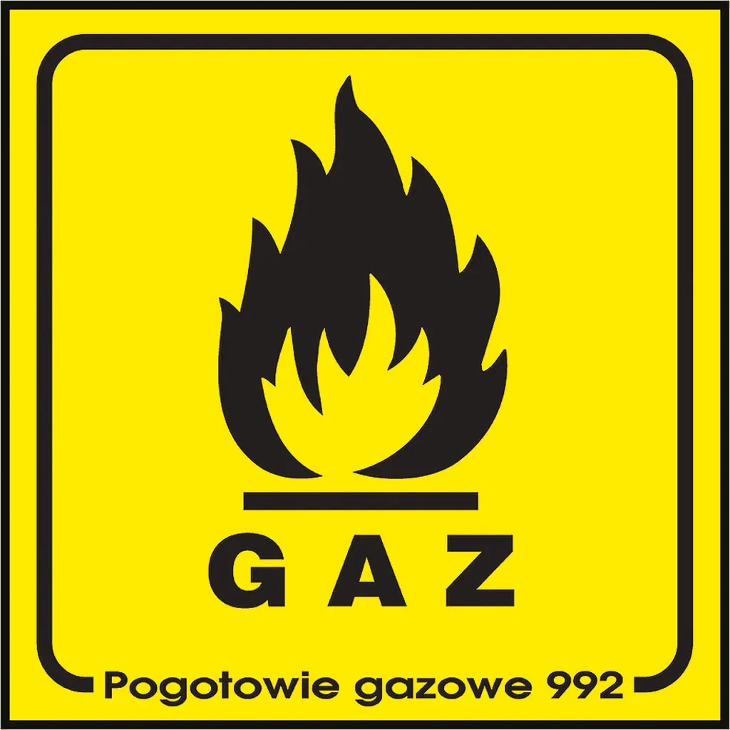 Znak bezpieczeństwa o żółtym tle z czarną grafiką płomienia i napisem „GAZ” w dolnej części. Pod spodem dodatkowy napis „Pogotowie gazowe 992”.