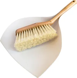 Zmiotka z drewnianym uchwytem i naturalnymi włosiami, spoczywa na białej, plastikowej szufelce.