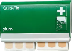 Zielony dozownik plastrów Quick Fix marki Plum. Na frontowej części znajduje się białe logo krzyża, a obok rysunek ilustrujący użycie. Z dozownika wystają plastry.